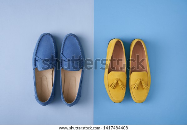 Blue suede man\'s and yellow woman\'s\
moccasins shoes over blue background, top\
view