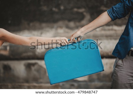 Blue suitcase in the hands of the bride and groom