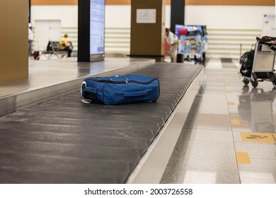 A blue suitcase on a conveyor belt at the international airport. Baggage claim point. Baggage claim at the airport