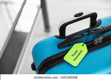 Blue suitcase with TRAVEL INSURANCE label indoors, closeup. Space for text - Powered by Shutterstock