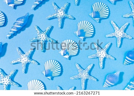 Blue summer background of a pattern of decorative glass sea conch. Starfish, sea conch, scallop