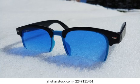 blue sunglasses on snow in sunnyday