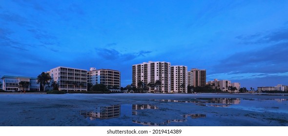 Blue sunset on Fort Myers Beach fills the sky behind timeshares, hotels and apartment buildings.