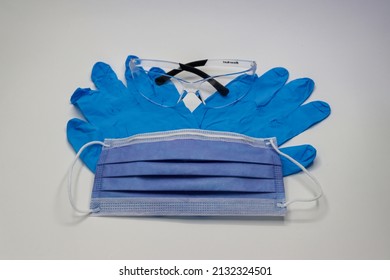 Blue Surgical Glove With Medical Mask And Eye Protection Goggles On White Background