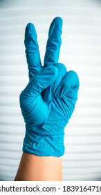 Blue Surgical Gloves Giving The Peace Sign