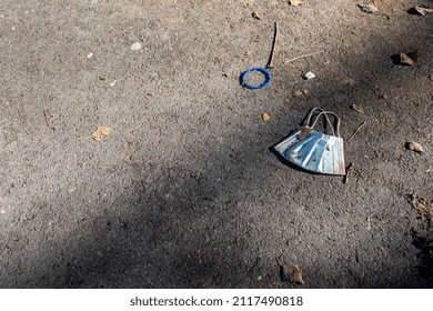 Blue Surgical Mask Abandoned On The Ground After Being Used During The Covid Pandemic