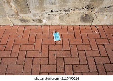 Blue Surgical Mask Abandoned On The Ground After Being Used During The Covid Pandemic