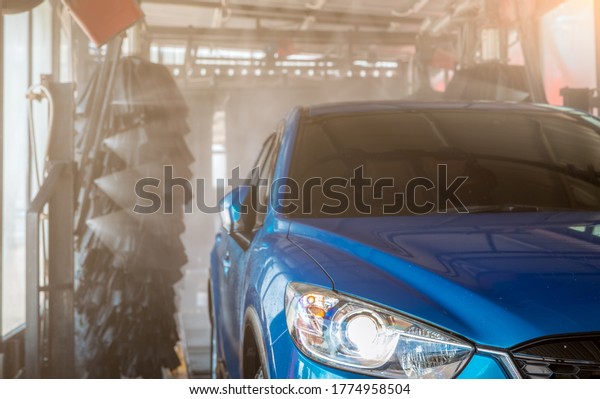 Blue SUV car washing by automatic car washing\
machine. Auto care. Car cleaning with high pressure water spray\
after clean by auto brush. Car cleaning before waxing service.\
Carwash service business.