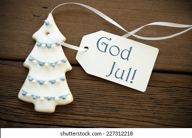 The Blue Swedish Words God Jul as Christmas Greetings on a white Label with Christmas Tree Cookie