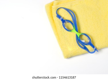 Blue Swimming Goggles On A Yellow Towel. Space For Text. Flat Top View

