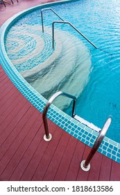 Blue swimming pool with steel ladders and red wooden plank deck.