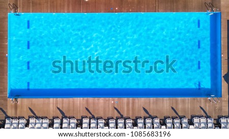 blue swimming pool summer vacation with white sun beds, top view
