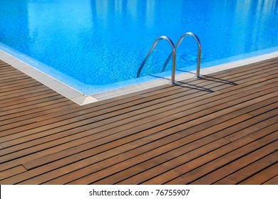 blue swimming pool with teak wood flooring stripes summer vacation - Powered by Shutterstock