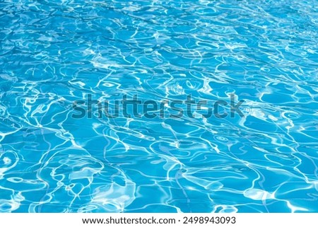 Blue swimming pool water surface and ripple wave background. Summer abstract reflection caustics in swimming pool.