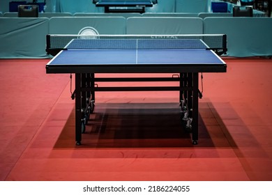 Blue table tennis or pingpong table is settle on a red, orange floor of the indoor court stadium for competitions tournament.
