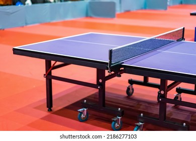 Blue Table Tennis Or Pingpong Table Is Settle On A Red, Orange Floor Of The Indoor Court Stadium For Competitions Tournament.