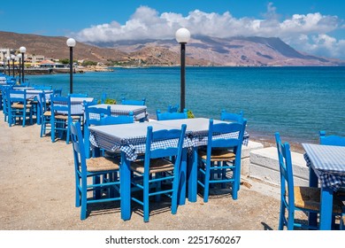 Blue tables and chairs in traditional Greek taverna on sea coast. Kissamos, Crete, Greece