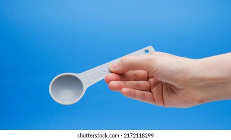 Blue Tablespoon Measuring Spoon At Angle In Hand