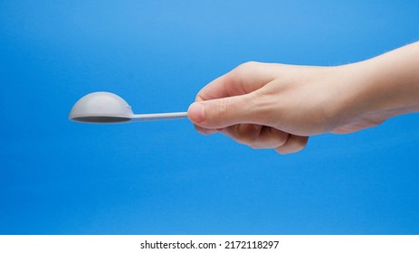 Blue Tablespoon Measuring Spoon Upside Down In Hand