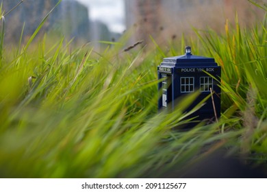 Blue Tardis Toy In Green Grass Closeup. Time Machine From Doctor Who TV Series, Classic British Object. Old Police Box In London.