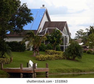 Blue Tarp On Roof Of Tropical Home After Hurricane Damage