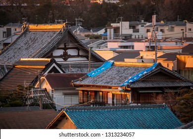 Blue Tarp With Sandbags On Pitched Roof Of Traditional Japanese House Damaged By Strong Typhoon Winds