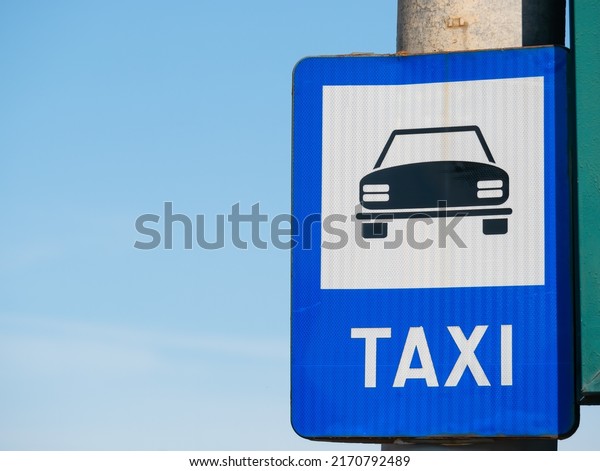Blue taxi sign\
station against blue sky.