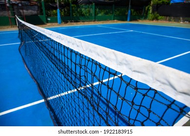 Blue Tennis Court With Net In Park. Empty Sport Field Photo. Hard Cover For Lawn Tennis. Summer Sport Activity Outdoor. White Markup On Blue Court. Sunny Day On Tennis Court. Sport Field In Park