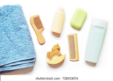 Blue Terry Towel, Wooden Comb, Toy Horse, Shampoo Bottle, Hair Balm, Green Soap On A White Background. Flat Lay Baby Bath Products, Natural Organic Cosmetics. Still Life Beauty Products Photo