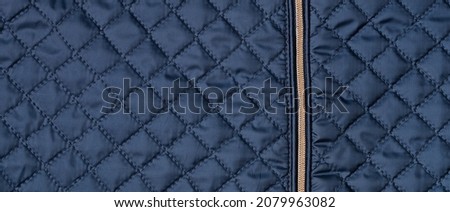 Blue texture of puffer, padded, down jacket. Background of urban winter outfit. Quilted pattern banner