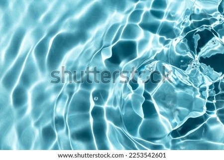 Blue textured background of waves with ripples on the water. Close-up, selective focus, defocus