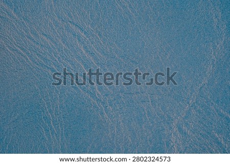 Blue textured surface with subtle light reflections.