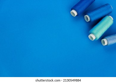 Blue thread. A set of spools of sewing thread. Several spools of thread in different shades of blue on a blue background. place for text