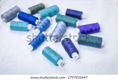 Blue thread spools arranged on white surface, sewing, threads, crafting