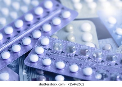 Blue tone of oral contraceptive pill on pharmacy counter with colorful pills strips background.