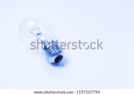 Blue toned incandescent lamp buld on light blue background with copy space.