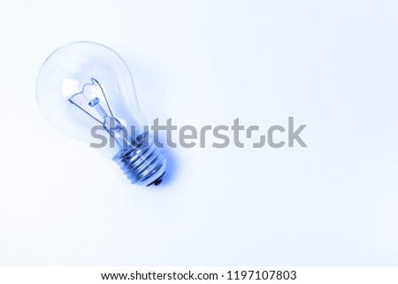 Blue toned incandescent lamp buld on light blue background with copy space.