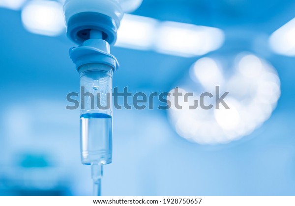 Blue tone.Intravenous fluid infusion during\
advance surgery inside operating room.Surgeon doing emergency\
surgery.Saline pump set drip to blood loss patient with blur\
background.Medical\
concept.