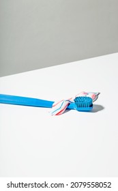 Blue Toothbrush With Squeezed Out Red White And Blue Toothpaste Lies On Light Background