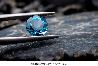 Blue Topaz Gemstone Jewelry Photo With Black Stone And Dark Lighting.