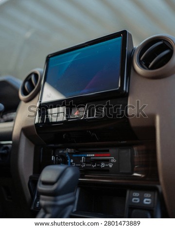 Blue touchscreen display on handheld control unit with buttons switches and hardware components photographed up close