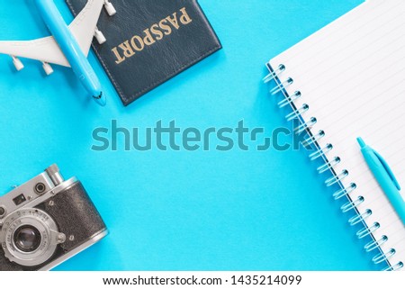 Blue toy airplane with a passport and vintage camera on light blue background. Flat lay with copy space for air travel planning or ticket fare and visa or booking concept