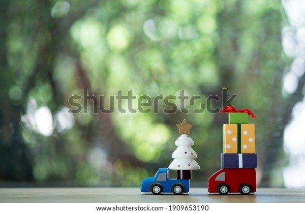 Blue toy car\
carrying gift box and red toy car carrying a christmas tree.\
Christmas holiday celebration\
concept