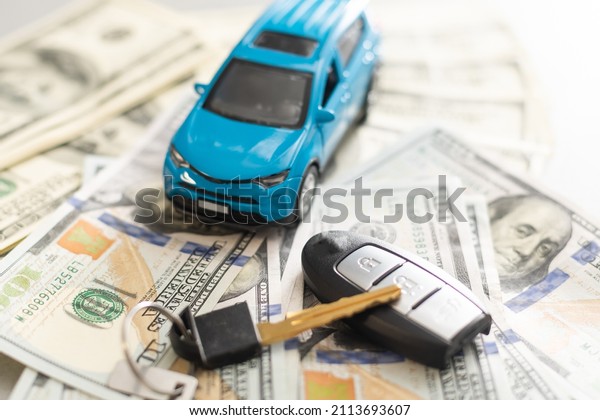 blue toy\
car with money and car key on wooden\
table.