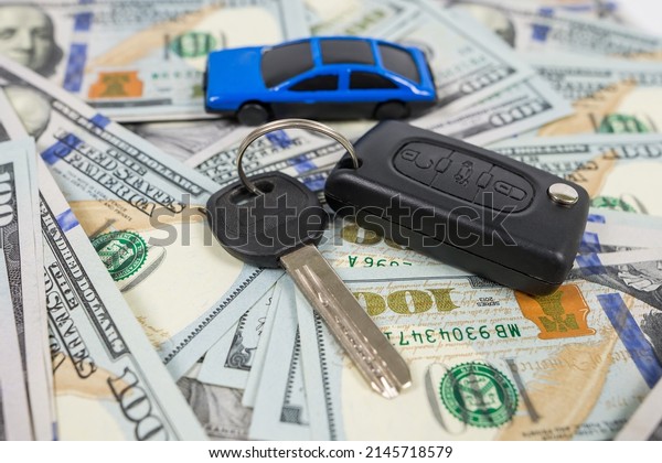 blue toy car with\
money and car key on white
