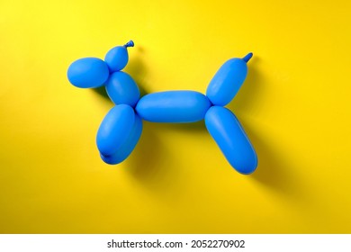 Blue Toy Dog From A Long Inflatable Ball, Top View, On A Yellow Background