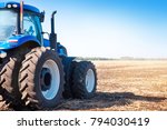 Blue tractor on the background of an empty field and a clear blue sky