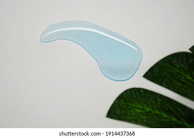 Blue transparent drop on white background with green leaf of palm tree. - Shutterstock ID 1914437368