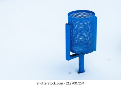 A blue trash can against a background of bright white snow