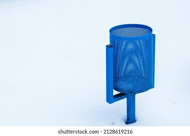 A blue trash can against a background of bright white snow